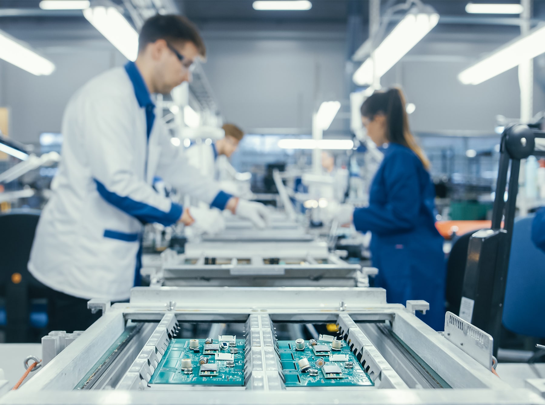 Shot of an Electronics Factory Workers Assembling Circuit Boards by Hand While it Stands on the Assembly Line. High Tech Factory Facility.